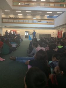 Jonathan Desrosiers speaking to the student body of Hayden-McFadden Elementary School as seen from the back of the room.