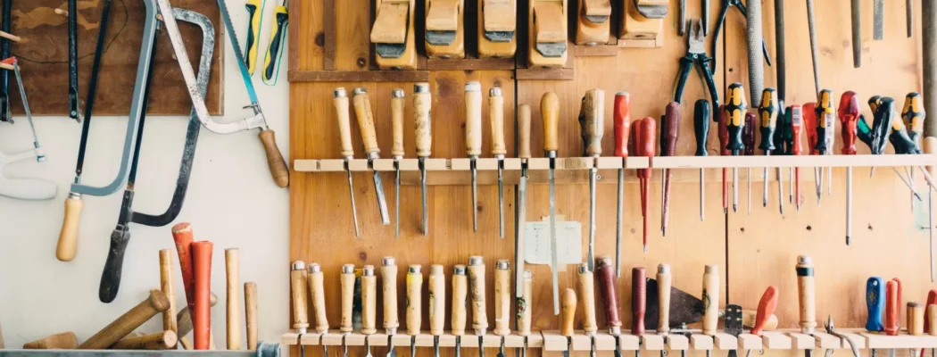 A workbench in front of a tool rack on the wall with saws and chisels