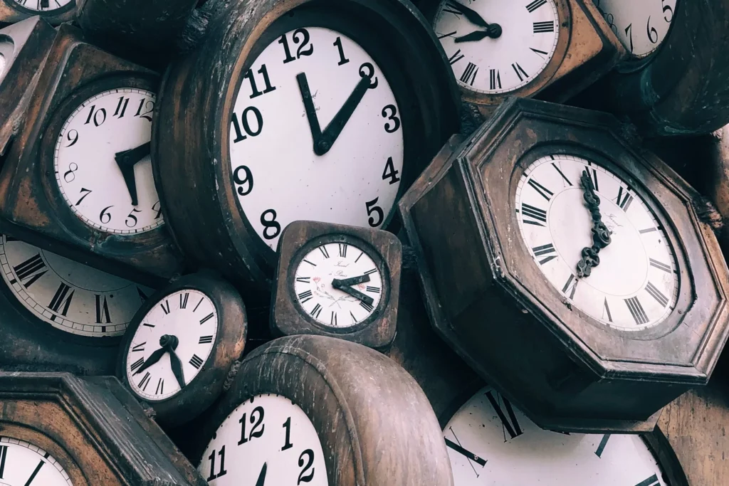 A pile of old wooden analog clocks