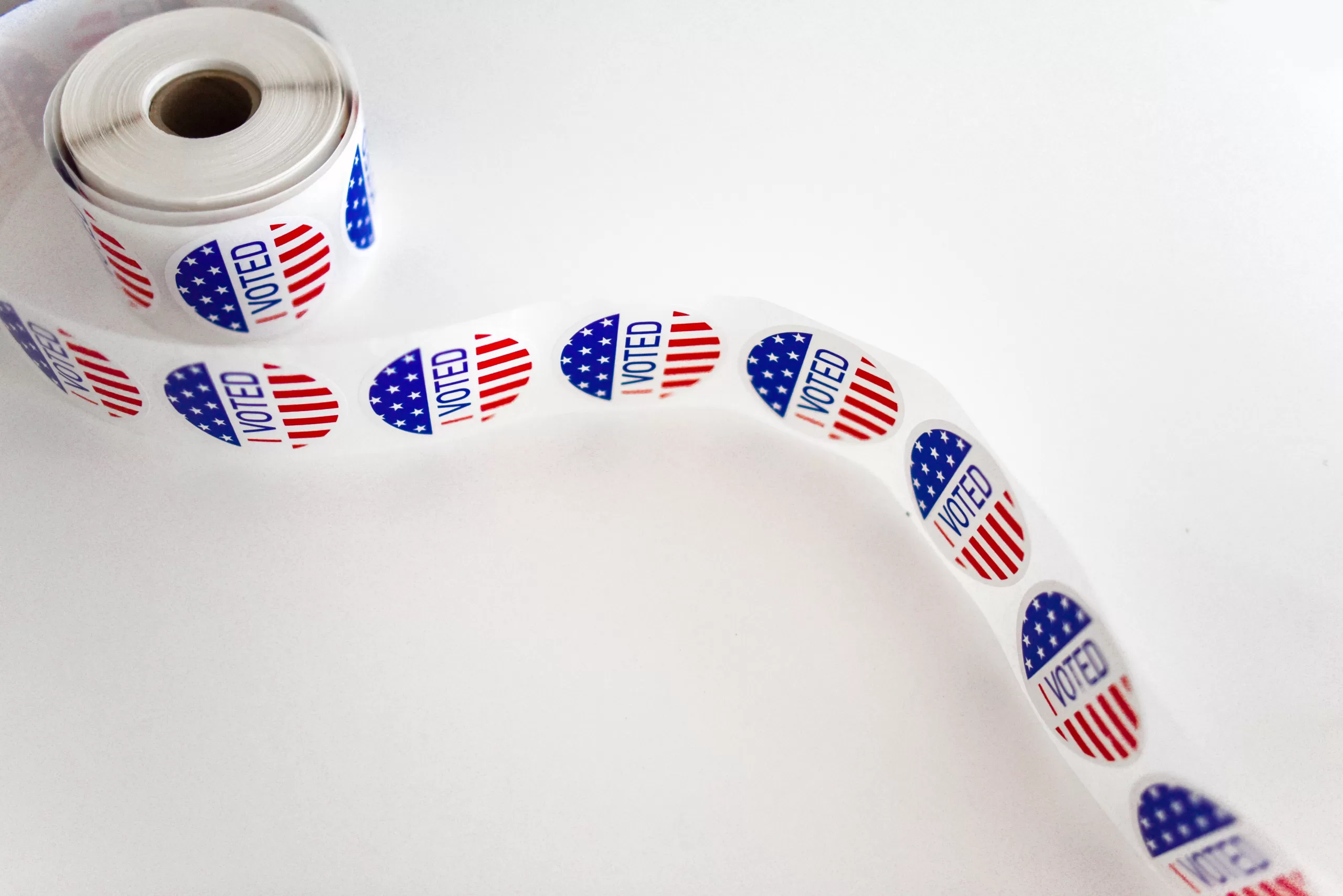 A roll of "I voted" stickers with the end loose on a white surface