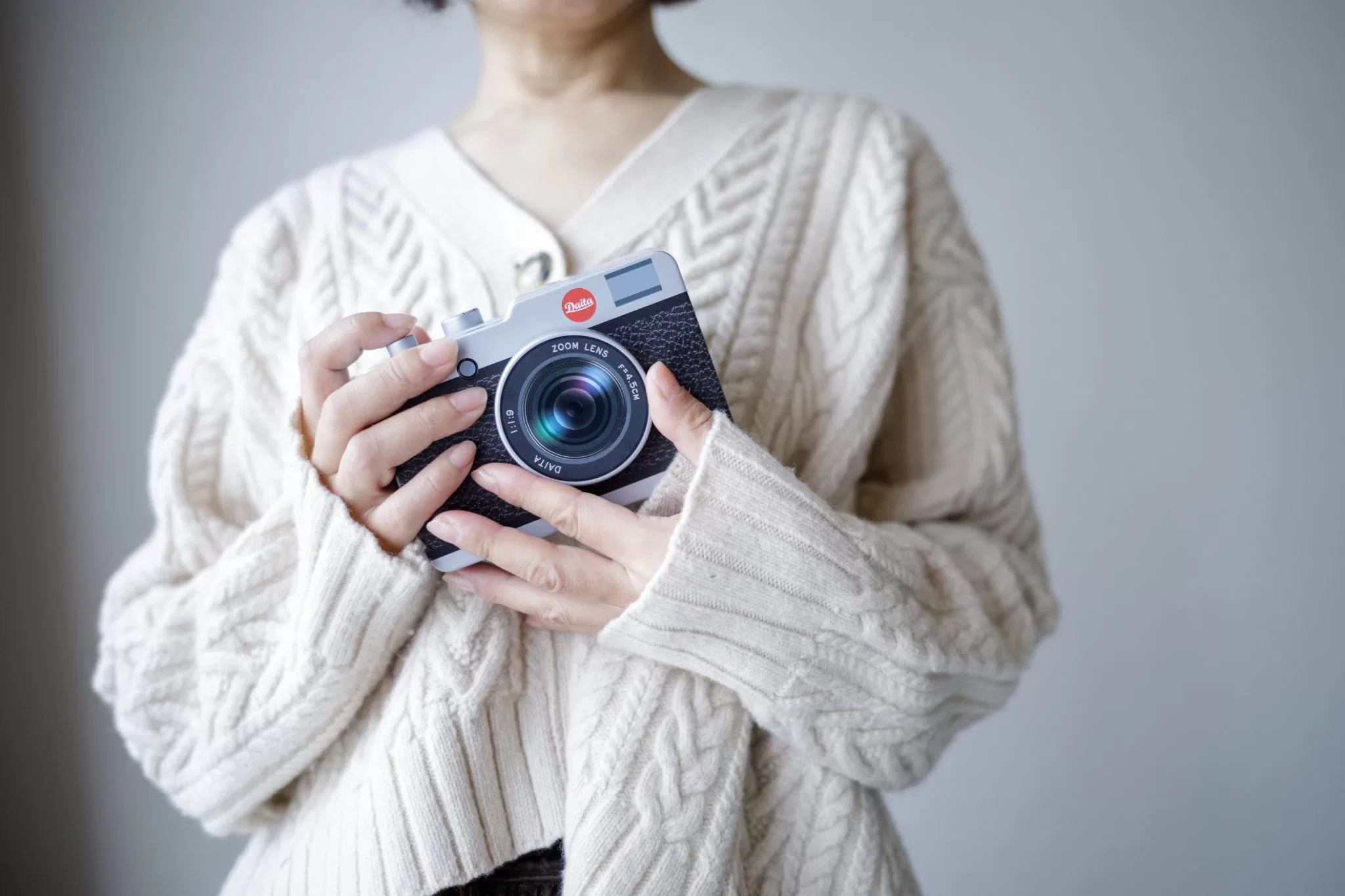 A woman holding Daita camera with two hands in front of her.