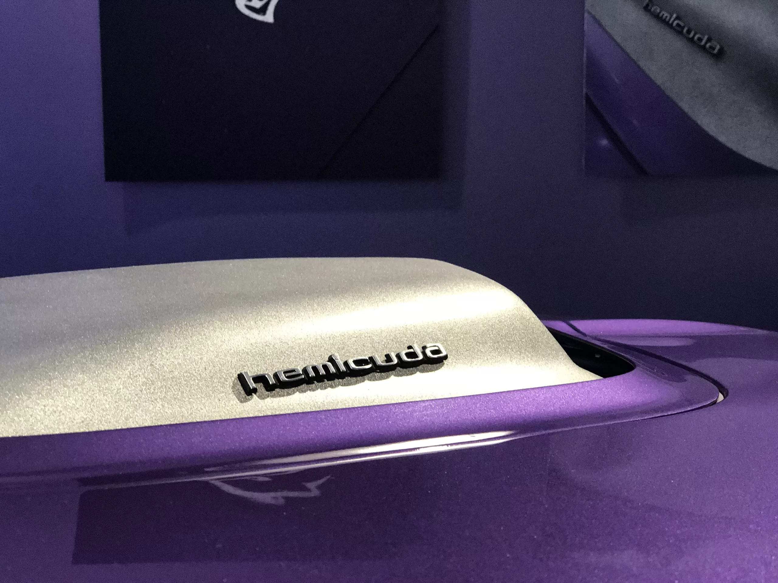 A close up of the hood scoop on a 1970 Plymouth Hemi 'Cuda hard top at the Newport Car Museum. The scoop is silver and the rest of the car is "Plum Crazy" purple.