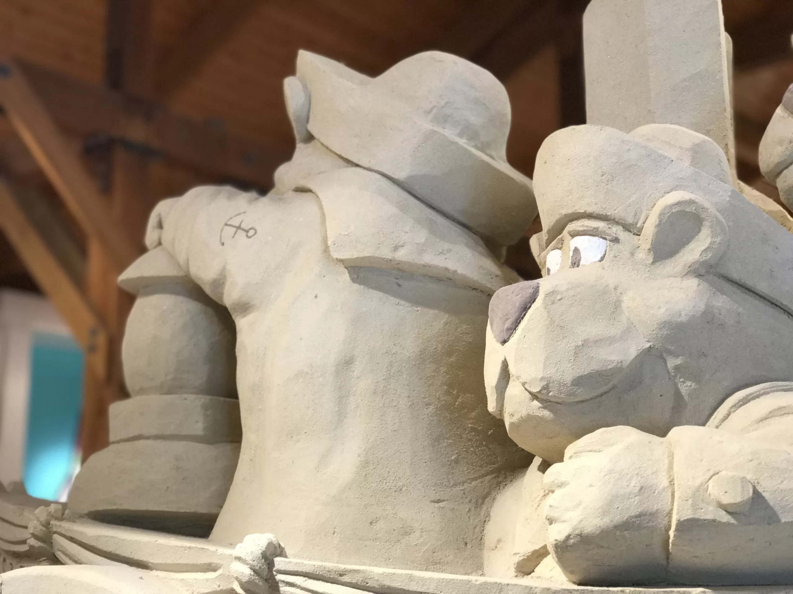 A sand sculpture of bears on a boat wearing sailing uniforms inside of Cuffy's in West Dennis, Massachusetts. One bear's face is visible, looking out into the distance.