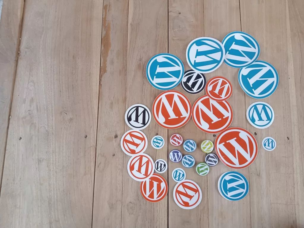 WordPress pins and stickers on a wooden floor