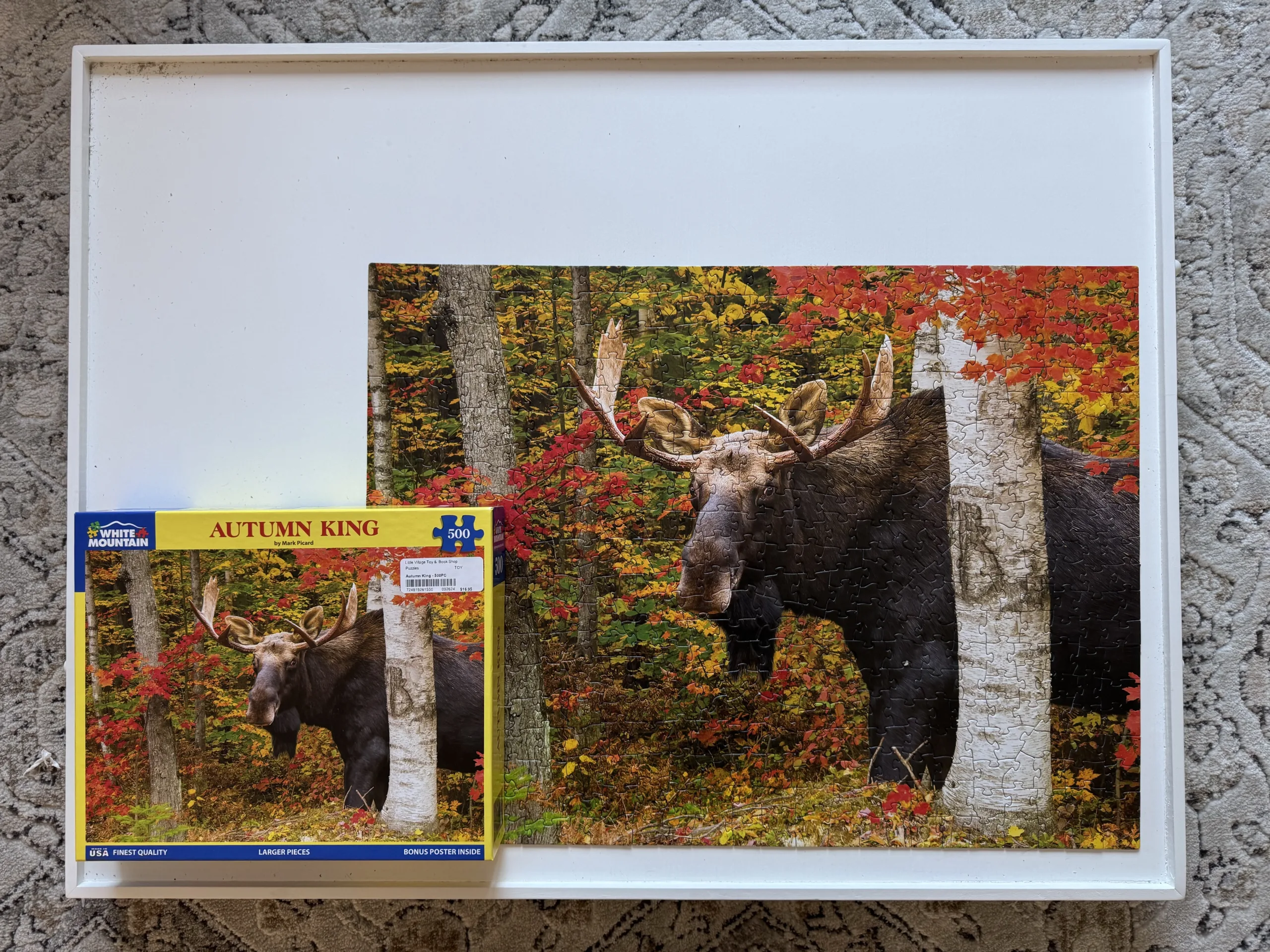 A completed "Autumn King" puzzle of an adult moose in the forest during the Fall season on a white puzzle board.