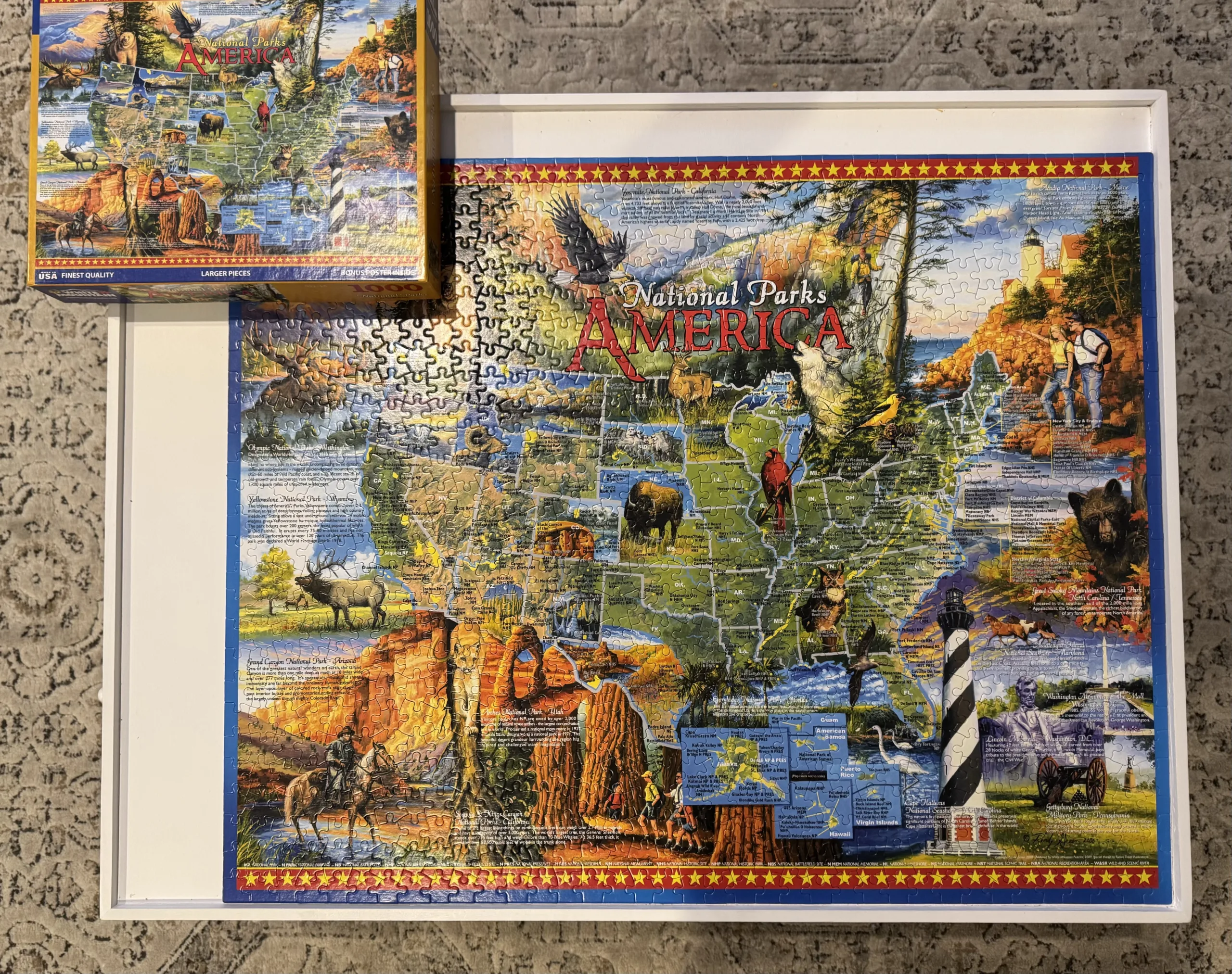 A completed National Parks 1,000 piece puzzle from White Mountain Puzzles. The puzzle is a map of the United States with scenic photographs of various national parks surrounding it. The puzzle is on a white rectangular puzzle board.